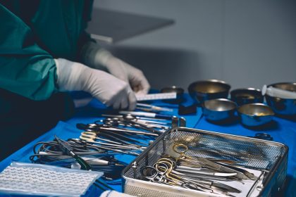 Profissional de saúde organiza instrumentos cirúrgicos em uma sala de operação.