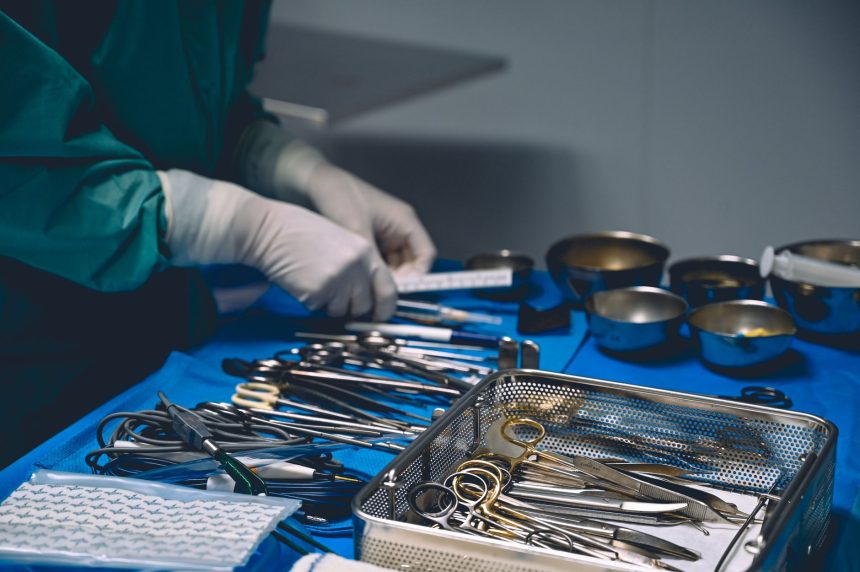 Profissional de saúde organiza instrumentos cirúrgicos em uma sala de operação.