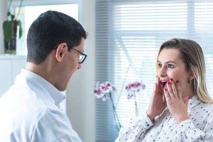 Mulher durante consulta médica, enquanto um profissional mede sua cintura em uma clínica.