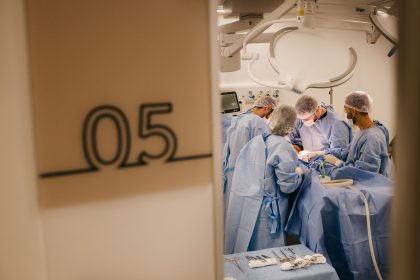 Equipe de cirurgiões realiza um procedimento em uma sala de operação hospitalar.