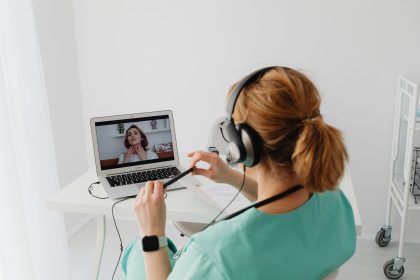 Médico realiza uma consulta virtual com um paciente por meio de um laptop em um consultório moderno.