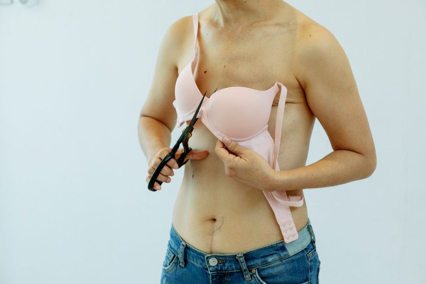 Mulher não identificada, vestindo jeans e um sutiã cortado com tesoura na altura do tórax, em referência ao pós-mastectomia.